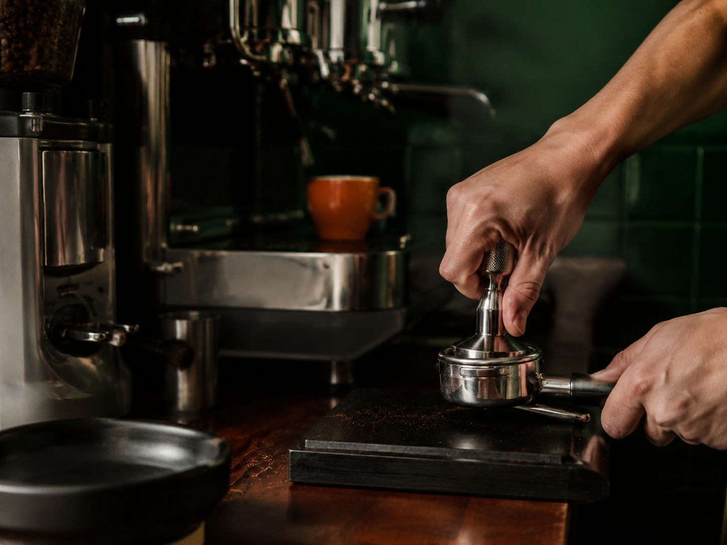 Barista tamping freshly ground coffee into a portafilter at the Chins counter